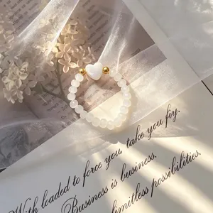 Close-up of an elegant shell heart beaded stretch ring on a decorative background