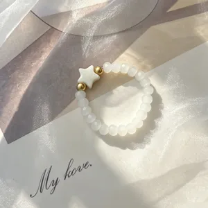 Close-up of bohemian beaded ring with shell star and gold accents on soft fabric
