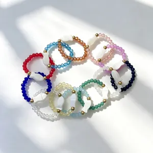 Detailed view of 12-color hand-woven beaded rings featuring white shell fish charms