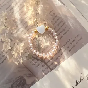 Detailed view of an elegant crystal beaded elastic ring featuring a white shell heart