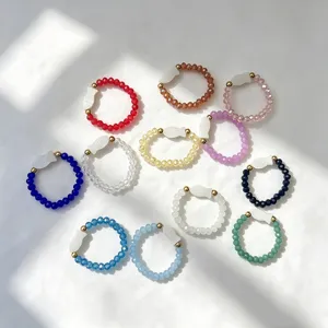Detailed view of twelve vibrant glass beaded elastic rings with white shell fish charms