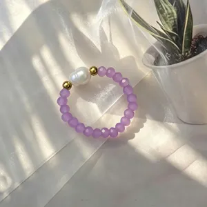 Detailaufnahme eines handgefertigten elastischen Rings mit lila Glasperlen und Naturperle