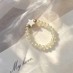 Detailed view of translucent glass beads and white shell star charm of the ring