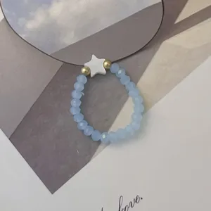 Macro detail view of light blue glass beaded ring with a white star shell charm