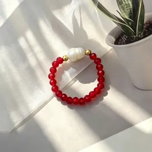 Nahaufnahme eines handgefertigten roten Glasperlenrings mit weißer Süßwasserperle.