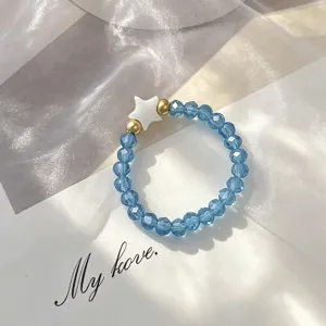 Macro view of bohemian blue glass beaded elastic ring with white shell star charm