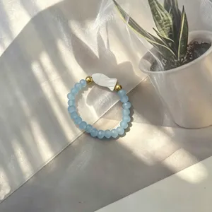 Detailed macro shot of handmade elastic ring with blue frosted beads and white shell fish