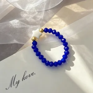 Close-up of bohemian blue glass beaded ring with shell star and gold accents