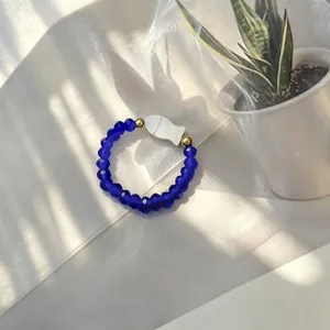 Detailed view of handmade blue glass bead elastic ring with white shell fish charm