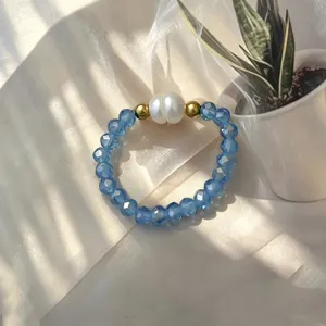 Detailansicht von blauen Glasperlen und einer Süßwasserperle auf einem Stretchring.