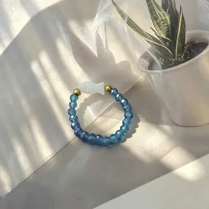 Detail view of handmade beaded elastic ring with blue glass beads and shell fish charm