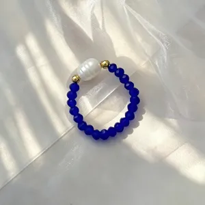 Nahaufnahme eines elastischen Rings mit natürlicher Süßwasserperle und blauen Glasperlen