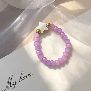 Detailed view of purple beaded ring with shell star charm and golden beads for women.