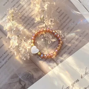 Detail showing white shell heart charm on champagne crystal glass beaded elastic ring