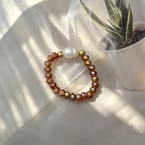 Detailansicht eines handgefertigten Perlenrings mit Bernsteinglasperlen und Perle.