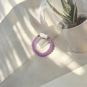 Detailed macro view of a purple glass beaded elastic ring with a shell fish charm.