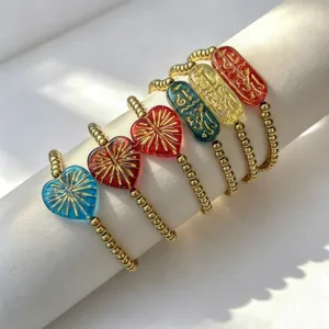 Detailansicht bunter Herz- und Runenarmbänder aus Glas mit goldener Edelstahloberfläche.