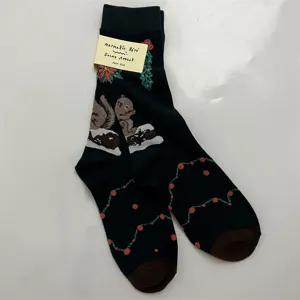 Close-up detail of knitted cotton socks featuring cute squirrel and forest Christmas print.