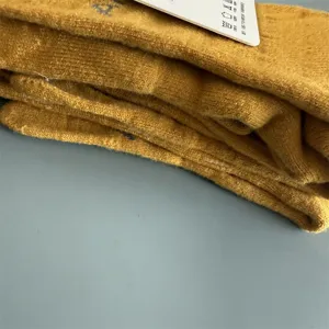 Nahaufnahme von gelben Strick-Zehensocken mit Frottee und praktischem Pflegeetikett.