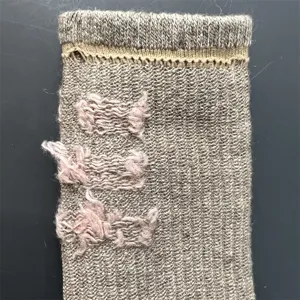 Primo piano del dettaglio del tessuto della calza in lana con trama rosa per escursionismo.