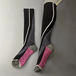 Dettaglio ravvicinato di calze da sci termiche in lana merino nera e rosa con spugna.