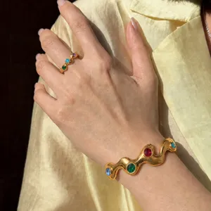 Detailed shot of vintage gold wavy bangle and ring set with colorful round gemstones