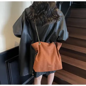 Gros plan d'un sac seau rétro en daim marron avec une bandoulière en chaîne dorée sur mannequin
