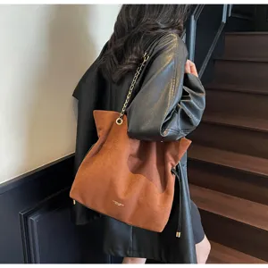 Stylish vintage brown suede bucket bag with gold chain strap carried by a model