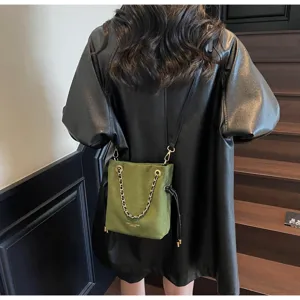 Vue arrière d'une femme portant un sac seau en suédine vert olive avec chaîne dorée
