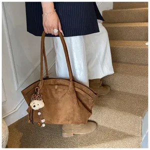 Elegante braune Tragetasche aus Wildlederimitat mit süßem Bärenanhänger für Damen.