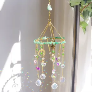 Dettaglio di acchiappasole in cristallo naturale con ciondoli stella e luna e riflessi arcobaleno