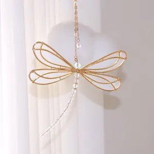 Close-up of golden wire dragonfly suncatcher with crystal bead tail against a soft background