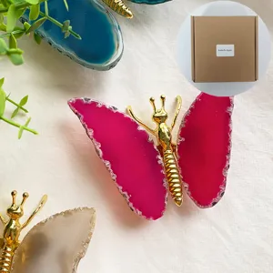 Detail of pink butterfly agate ornament with gold metal body and natural stone wings
