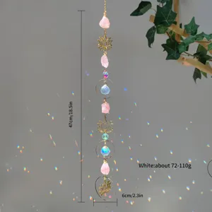 Pink raw crystal suncatcher hanging ornament with lotus charms creating rainbow reflections