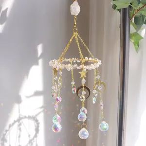 Primo piano di acchiappasole in cristallo con ciondoli luna e stella e riflessi arcobaleno.
