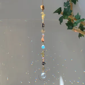 Close-up of crystal suncatcher with natural stones and witch hat charms in sunlight