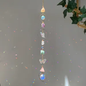 Close-up of a natural crystal suncatcher hanging against a light gray wall with rainbows