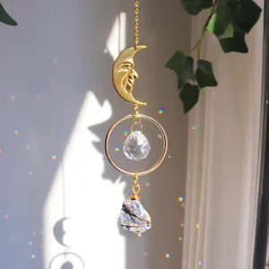 Detailansicht eines goldenen Mondgesicht-Sonnenfängers mit Kristallprisma und Rohstein
