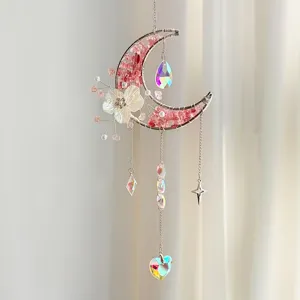 Detail van maanvanger met roze stenen en een iriserend hartvormig kristalprisma