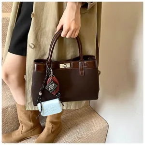 Detail showing a vintage dark brown tote bag with lock closure and decorative charms.