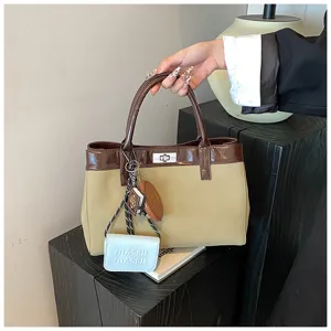 Detailed view of a retro khaki and brown patchwork tote bag with a silver lock and charms