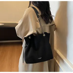 Vue arrière d'un sac seau en daim noir avec chaîne dorée porté par un mannequin