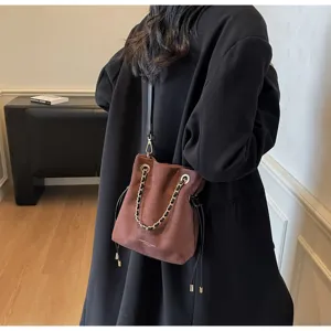 Close-up of vintage brown suede bucket bag with gold chain strap
