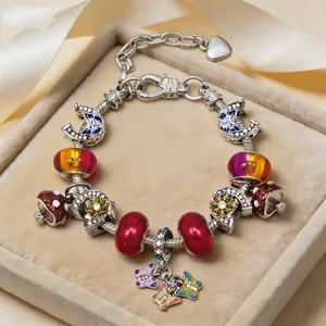 Dettaglio bracciale con ciondoli fai-da-te, farfalle e perle di vetro in confezione regalo.