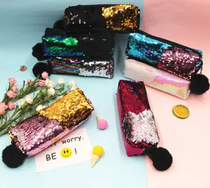Primer plano de estuches de lentejuelas de sirena reversibles con pompones negros.