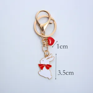 Detailed size view of a cute white rabbit keychain with a red bow and heart charm