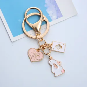 Close-up of gold-tone keychain with pink heart, white rabbit and Ace of Clubs charms