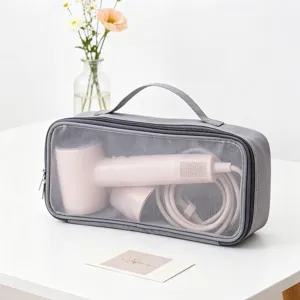 Borsa a rete grigia per riporre un asciugacapelli rosa su un tavolo bianco
