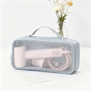 Dettaglio della borsa porta asciugacapelli grigia in rete con all'interno un phon rosa.