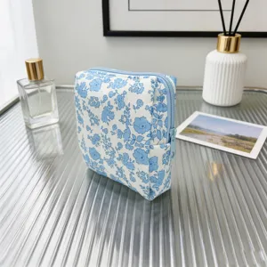 Primer plano de un neceser acolchado de flores azules sobre un escritorio de cristal